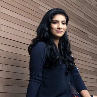 Anitha Devi Pillai, a Singaporean woman with long black hair. She wears a dark, floral-printed dress.